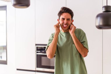 Genç melez adam mutfakta kulaklarını elleriyle kapatıyor..