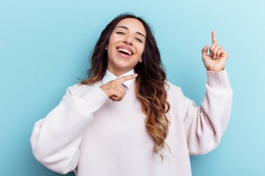 Genç Meksikalı kadın mavi arka planda izole edilmiş dans ediyor ve eğleniyor..