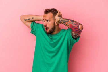 Pembe arka planda izole edilmiş dövmeleri olan genç beyaz bir adam çığlık atıyor, çok heyecanlı, tutkulu, bir şeyden memnun..