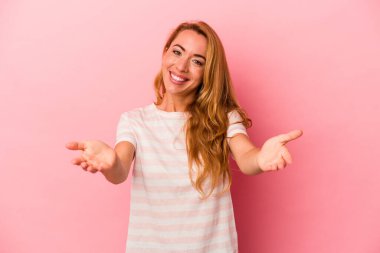 Pembe arka planda izole edilmiş beyaz sarışın kadın kameraya sarıldığı için kendinden emin hissediyor..