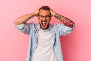 Pembe arka planda izole edilmiş dövmeleri olan genç beyaz bir adam çığlık atıyor, çok heyecanlı, tutkulu, bir şeyden memnun..
