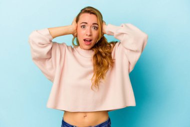 Kafkasyalı kadın mavi arka planda izole edilmiş. Kulaklarını elleriyle kapatıyor. Gürültülü sesler duymamaya çalışıyor..