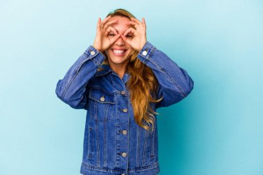 Beyaz kadın mavi arka planda izole edilmiş. Heyecanlı. Göze göz hareketi yapıyor..