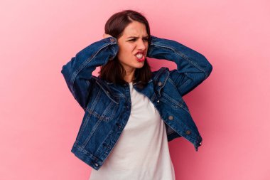 Pembe arka planda izole edilmiş genç beyaz kadın kulaklarını elleriyle kapatıyor..