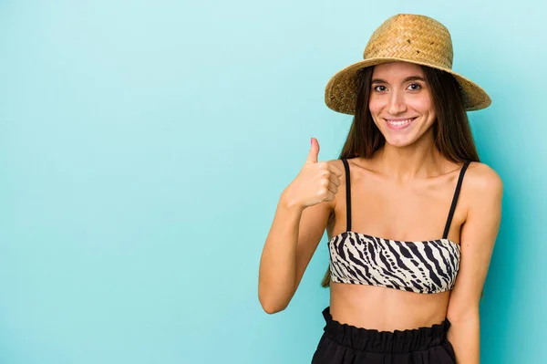 年轻的高加索女人穿着蓝色背景的比基尼去海滩 面带微笑 竖起大拇指 — 图库照片