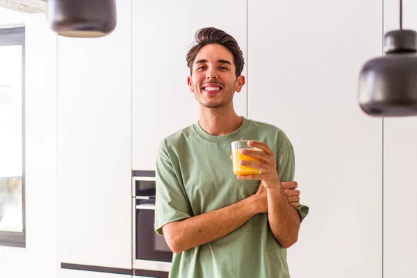 Joven Hombre Raza Mixta Bebiendo Jugo Naranja Cocina Riendo Divirtiéndose — Foto de Stock
