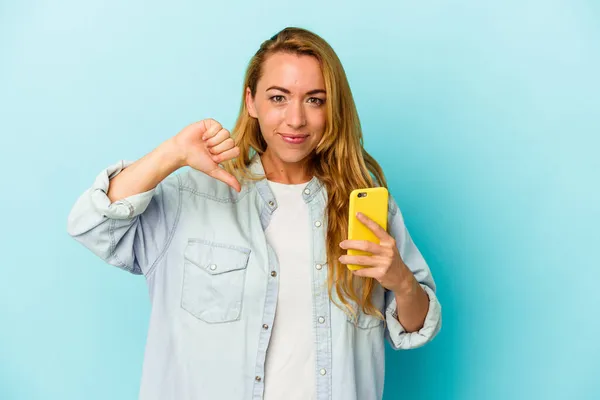 白人女人拿着手机 蓝色背景的人表现出不喜欢的手势 大拇指朝下 不同意的概念 — 图库照片
