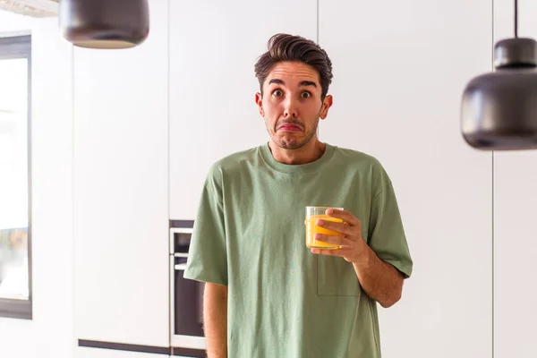 Joven Hombre Raza Mixta Bebiendo Jugo Naranja Cocina Encoge Hombros — Foto de Stock