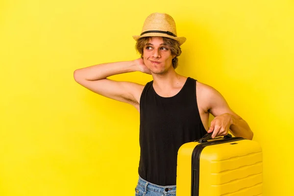頭の後ろに触れる黄色の背景に隔離された旅行に行く化粧を持つ若い白人男性 思考と選択をする — ストック写真