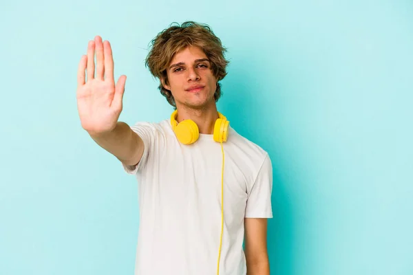 Ung Kaukasier Man Lyssnar Musik Isolerad Blå Bakgrund Står Med — Stockfoto