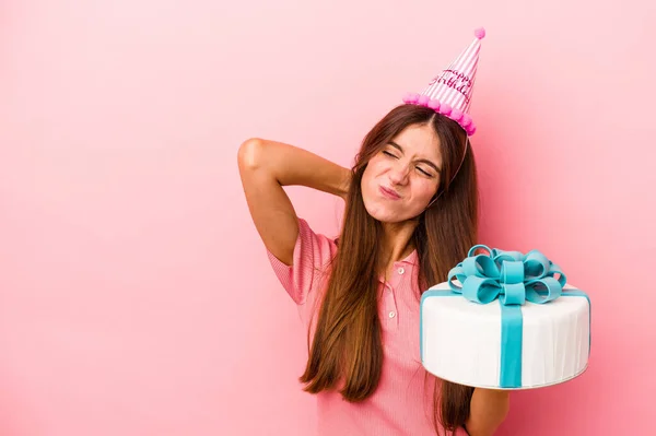 Young caucasian woman celebrating a birthday isolated on pink background touching back of head, thinking and making a choice.