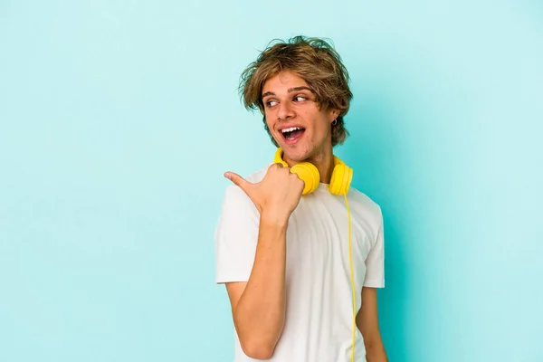 Ung Kaukasier Man Lyssnar Musik Isolerad Blå Bakgrundspunkter Med Tumme — Stockfoto