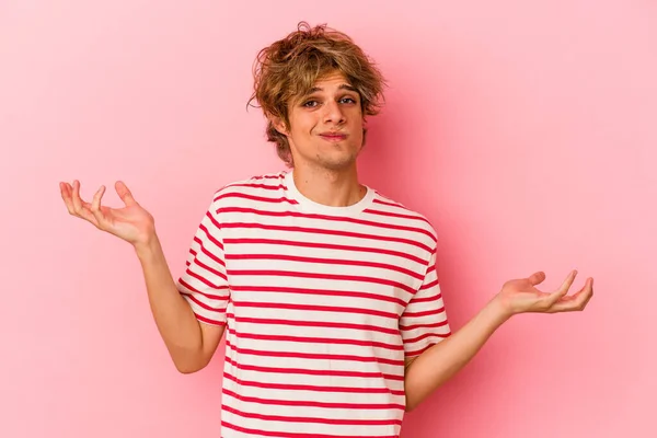 Jonge Blanke Man Met Make Geïsoleerd Roze Achtergrond Twijfelen Schouders — Stockfoto
