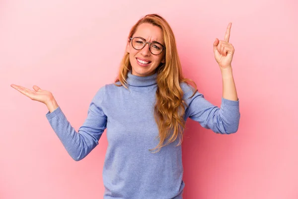 Mujer Rubia Caucásica Aislada Sobre Fondo Rosa Sosteniendo Mostrando Producto —  Fotos de Stock