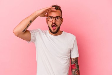 Pembe arka planda izole edilmiş beyaz dövmeli genç adam yüksek sesle bağırıyor, gözleri açık ve elleri gergin tutuyor..