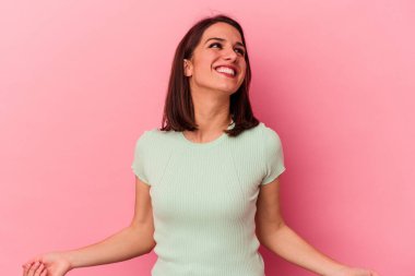 Genç beyaz kadın pembe arka planda izole edilmiş rahat ve mutlu bir şekilde gülüyor, boynunda dişlerini gösteriyor..