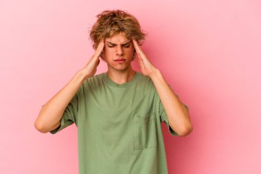 Makyajlı beyaz bir adam pembe arka planda izole edilmiş tapınaklara dokunuyor ve baş ağrısı çekiyor..