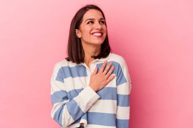 Pembe arka planda soyutlanmış beyaz bir kadın yüksek sesle gülüyor ve elini göğsüne koyuyor..