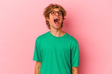 Makyajlı beyaz bir adam pembe arka planda izole edilmiş çok kızgın, öfkeli, hayal kırıklığına uğramış bağırıyor..