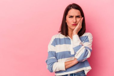 Pembe arka planda izole edilmiş genç beyaz kadın üzgün ve düşünceli, fotokopi alanına bakıyor..