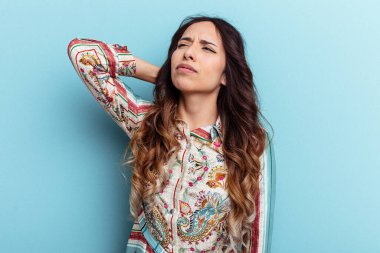 Genç Meksikalı bir kadın mavi arka planda izole edilmiş. Durağan yaşam tarzından dolayı boyun ağrısı çekiyor..