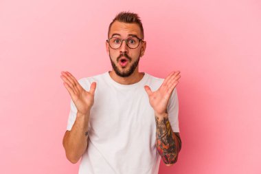 Pembe arka planda dövmeleri olan beyaz bir adam şaşırmış ve şok olmuştu..