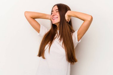 Beyaz arka planda soyutlanmış beyaz tenli genç bir kadın kendini güvende hissediyor, elleri başının arkasında..