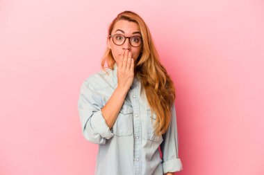 Pembe arka planda izole edilmiş beyaz sarışın kadın şok olmuş, ağzı ellerle kaplanmış, yeni bir şey keşfetmeye hevesli..