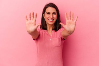 Pembe arka planda izole edilmiş genç beyaz kadın on numarayı elleriyle gösteriyor..