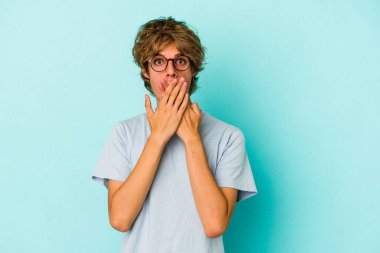 Mavi arka planda soyutlanmış, ağzı ellerle kaplanmış, yeni bir şey keşfetmeye hevesli beyaz bir genç..