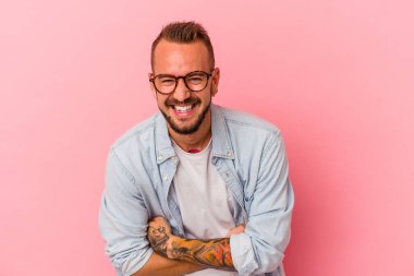 Pembe arka planda izole edilmiş dövmeleri olan beyaz bir adam gülüyor ve eğleniyor..