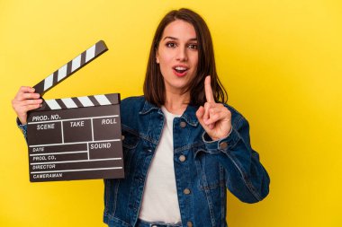 Sarı arka planda, bir fikri olan, ilham verici bir fikri olan, elinde klaket tutan beyaz bir kadın..