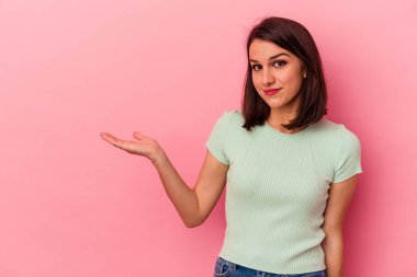 Pembe arka planda izole edilmiş genç beyaz kadın bir avuç içinde fotokopi alanı ve belinde bir el daha gösteriyor..