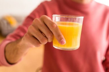 Genç melez adam mutfağında portakal suyu içiyor.