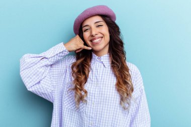 Mavi arka planda izole edilmiş genç Meksikalı kadın parmakları olan bir cep telefonu hareketi gösteriyor..