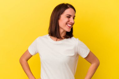 Sarı arka planda izole edilmiş genç beyaz kadın gülüyor ve gözlerini kapıyor, rahatlamış ve mutlu hissediyor..