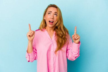 Beyaz kadın, mavi arka planda izole edilmiş, ağzı açık, üst tarafı işaret ediyor..