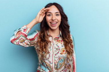 Mavi arka planda izole edilmiş genç Meksikalı kadın yüksek sesle bağırıyor, gözlerini açık ve ellerini gergin tutuyor..