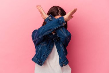 Pembe arka planda izole edilmiş genç beyaz kadın iki kolu çapraz tutuyor, inkar kavramı.