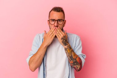 Pembe arka planda izole edilmiş, ağzı ellerle kaplanmış, yeni bir şey keşfetmeye hevesli, beyaz, genç bir adam..