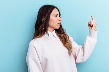 Mavi arka planda izole edilmiş genç Meksikalı kadın sanki seni davet ediyormuş gibi seni işaret ediyor..