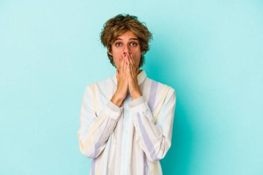Mavi arka planda soyutlanmış beyaz bir adam elleriyle ağzını kapatırken şok oldu..