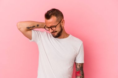 Pembe arka planda izole edilmiş beyaz dövmeli genç bir adam sabit yaşam tarzından dolayı boyun ağrısı çekiyor..
