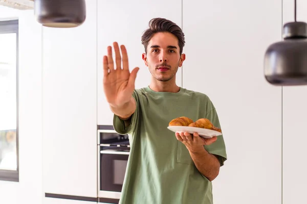 Young Mixed Race Man Eating Croissant Kitchen Morning Standing Outstretched — Stock Photo, Image