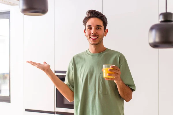 Joven Hombre Raza Mixta Bebiendo Jugo Naranja Cocina Mostrando Espacio — Foto de Stock