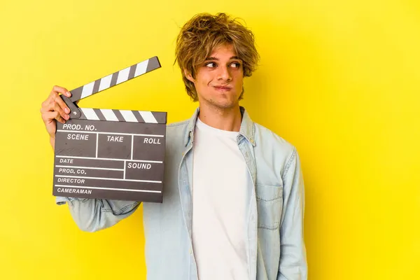 Young Caucasian Man Makeup Holding Clapperboard Isolated Yellow Background Confused — Stock Photo, Image
