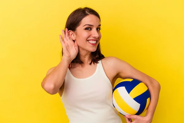 Молода Біла Жінка Грає Волейбол Ізольовано Жовтому Тлі Намагаючись Слухати — стокове фото