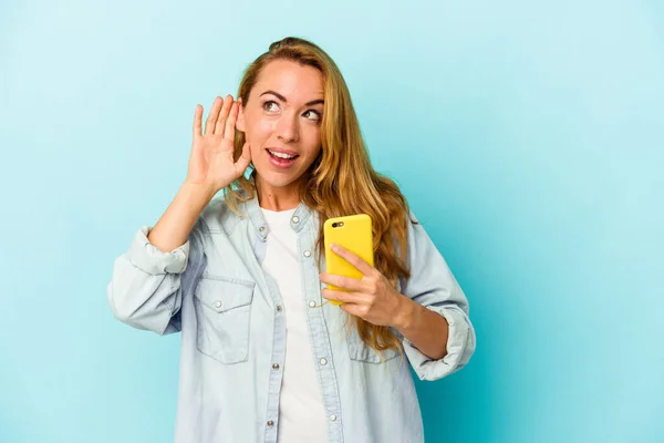 Kaukasiska Kvinna Som Håller Mobiltelefon Isolerad Blå Bakgrund Försöker Lyssna — Stockfoto