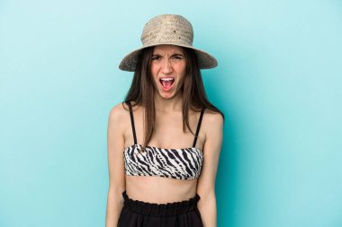 Genç beyaz kadın plaja gidiyor. Mavi arka planda izole edilmiş bikini giyiyor. Çok sinirli ve agresif bağırıyor..