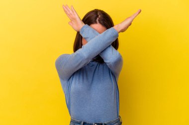 Sarı arka planda izole edilmiş genç beyaz kadın iki kolu çapraz tutuyor, inkar kavramı.